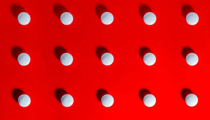 Vita runda tabletter på röd bakgrund