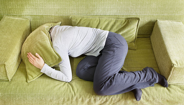 Dekorationsbild: Kvinna ligger på soffa och har ont i huvudet