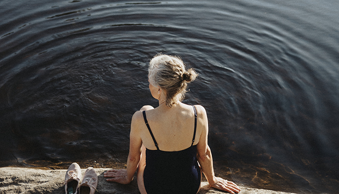 Dekorationsbild: Kvinna sitter vid vatten